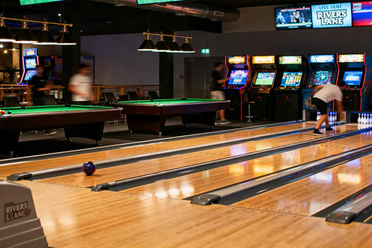 pexels-michal-pech-213601-757318 (1) Allée de bowling animée, tables de billard, bornes d'arcade, joueur lançant la boule, ambiance de loisir.
